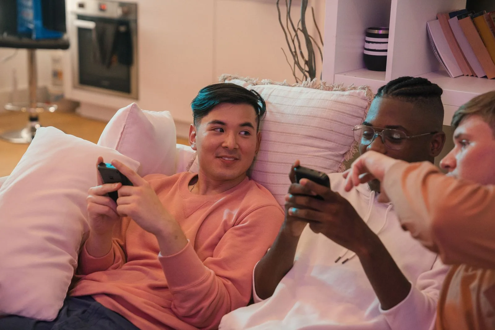 Drei Freunde, die zu Hause gemeinsam mit ihren Smartphones auf dem Sofa sitzen.